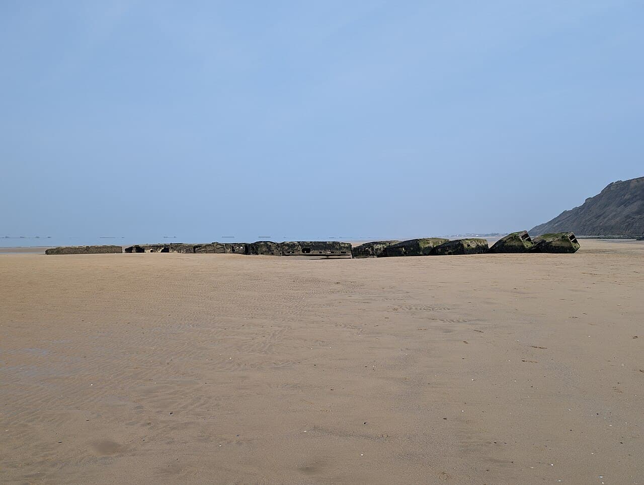 Concrete caissons of the Mulberry harbour resting on the sand at Arromanches at low tide
